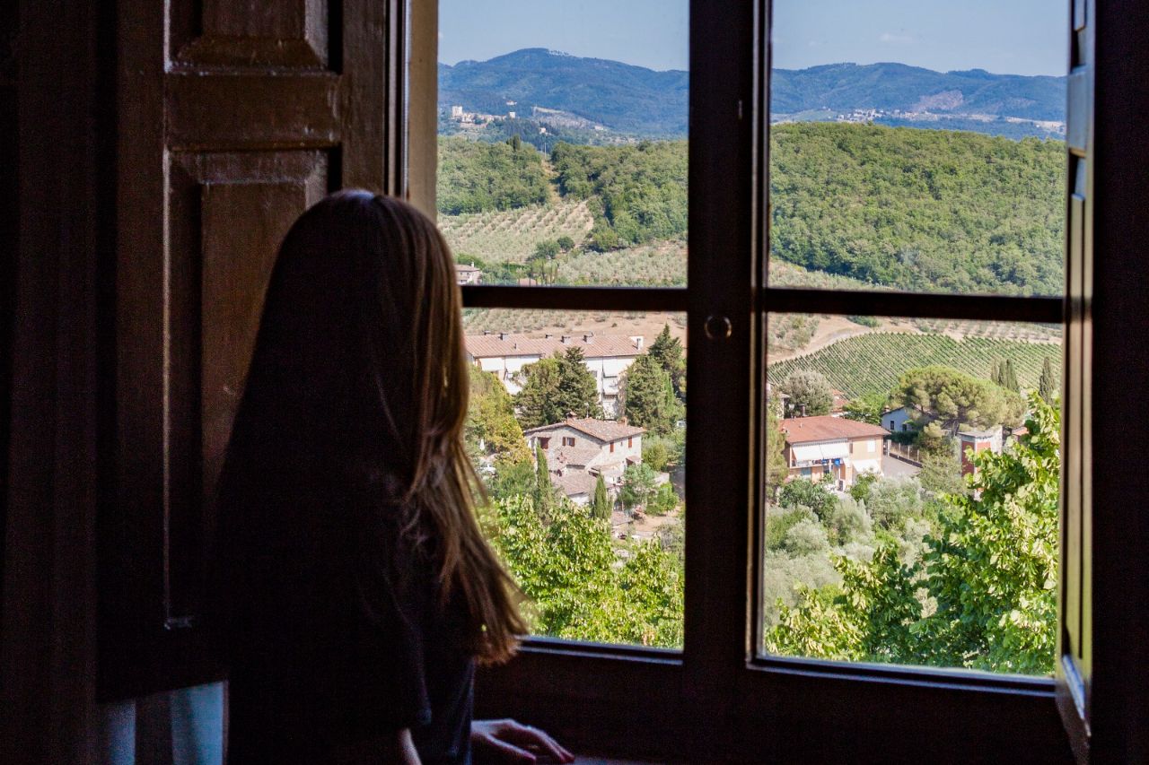 The girl enjoys the view of the panorama of Radda in Chianti from a window