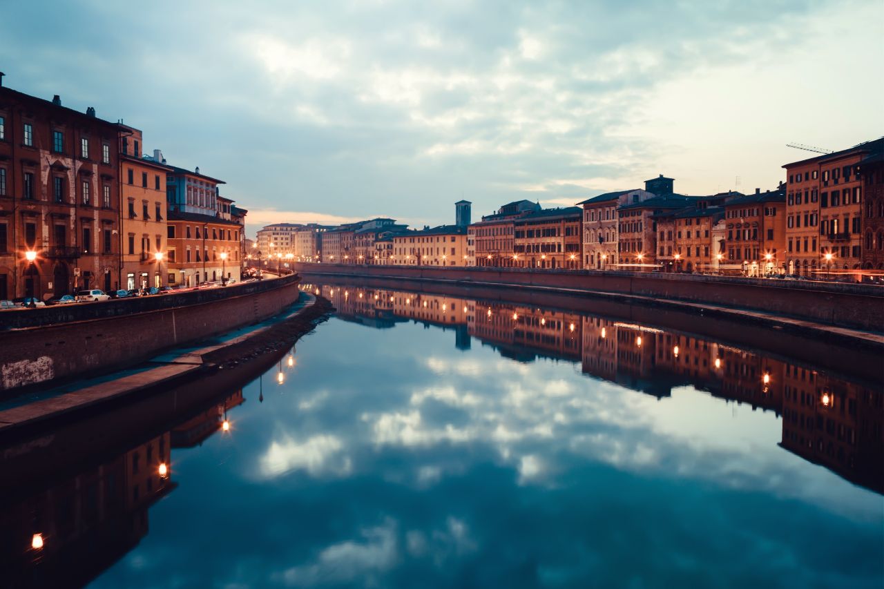 The Arno River in Pisa reflects the houses of the city.
