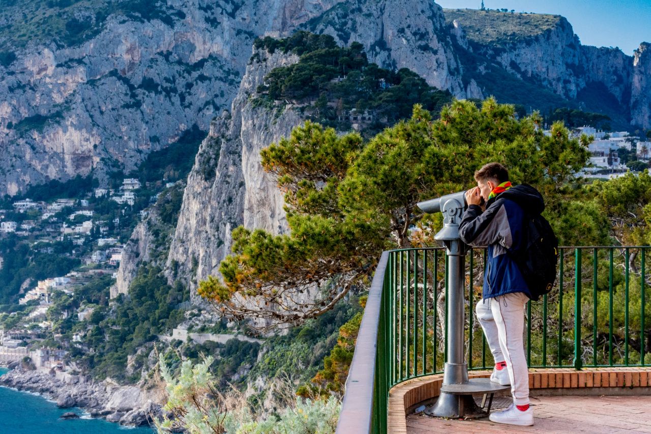 Using a spyglass, a tourist enjoys the view of the Isle of Capri