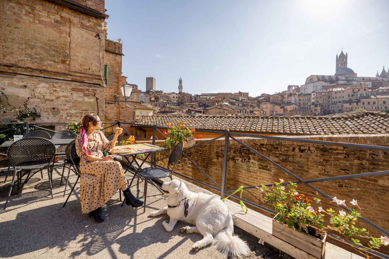 It's a sunny afternoon in Siena, and a girl and her dog are having an "aperitivo"