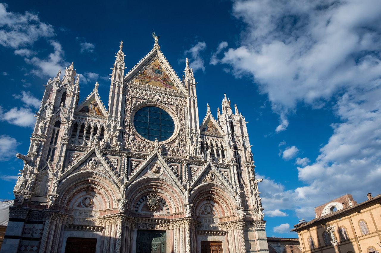 The view of the unique architectural beauty of Siena cathedral with white clouds, and blue sky background