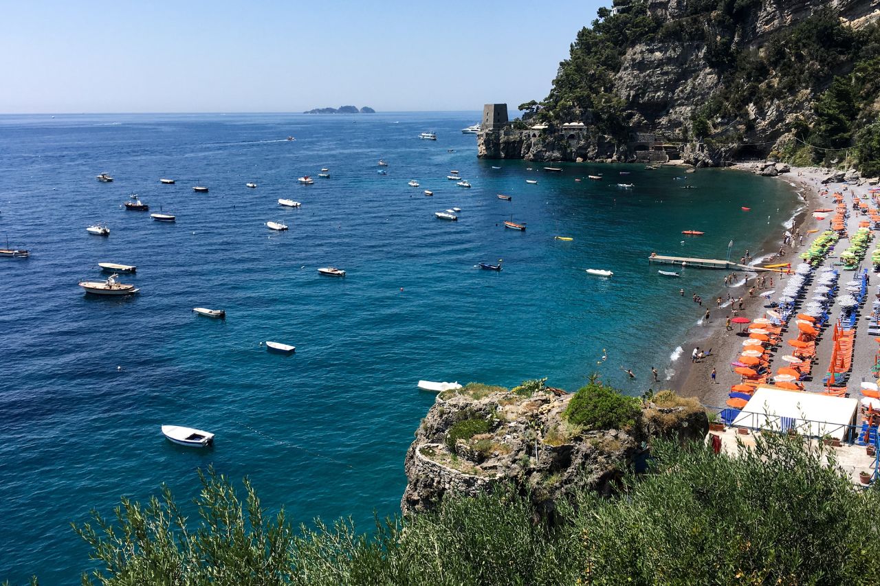 A sunny day on the Amalfi coast with many travelers enjoying swimming on the beach
