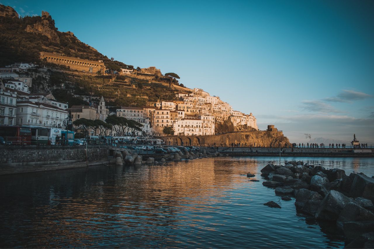 Sunset over the Amalfi coast with many travelers nearby.