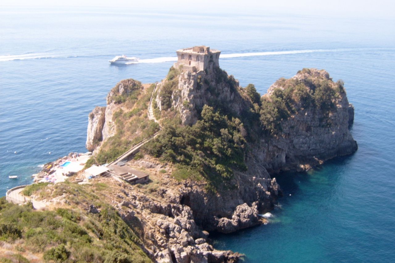An aerial view of the Tower of Silence on top of a rocky mountain near the sea in Conca dei Marini.
