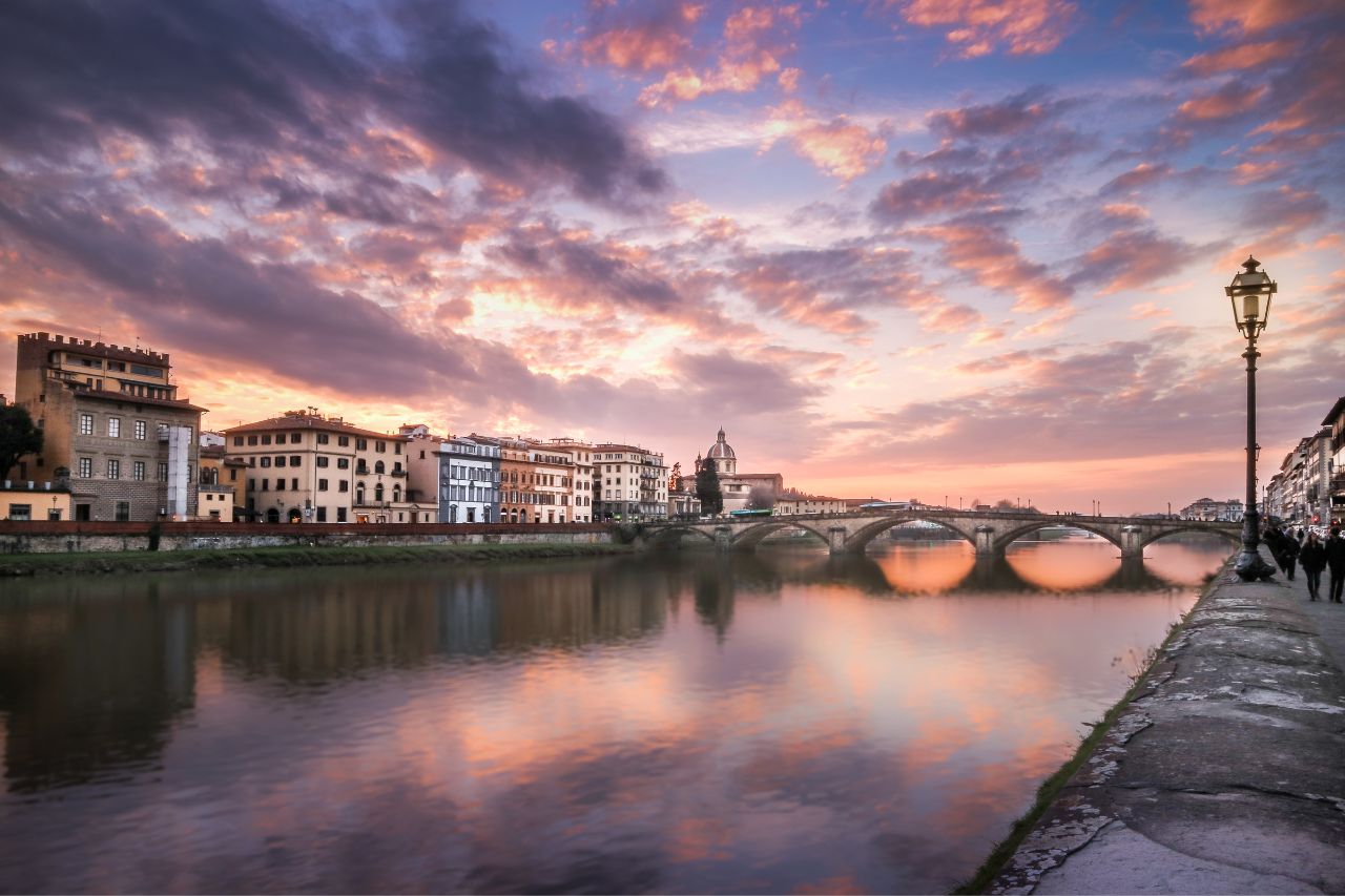 View of the Florence skyline, featuring historic architecture, red-tiled roofs, and the Arno River.
