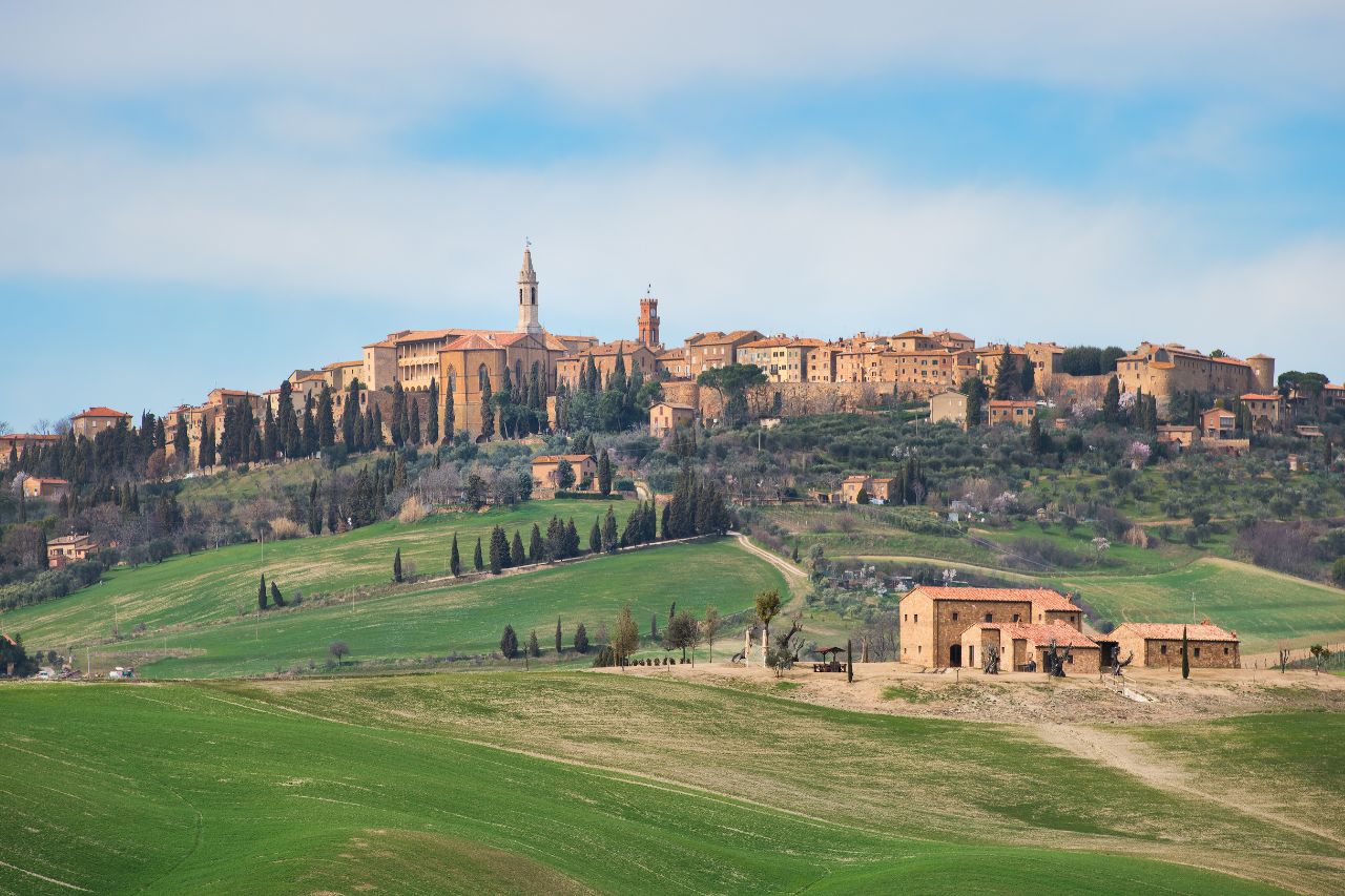 The green landscape of a Tuscan hill town with a view of cultural structures and houses