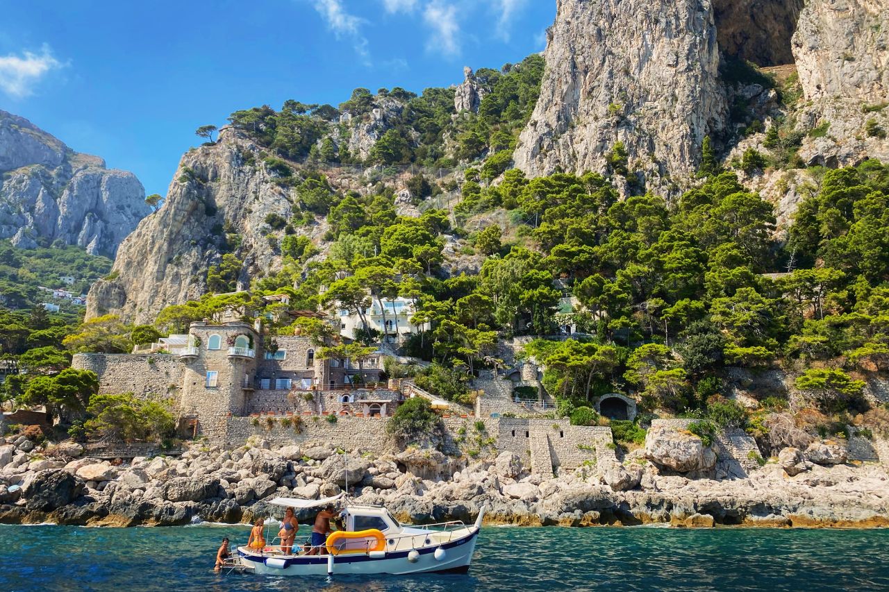 A family of tourists enjoy a tour boat while swimming on the island of Capri.