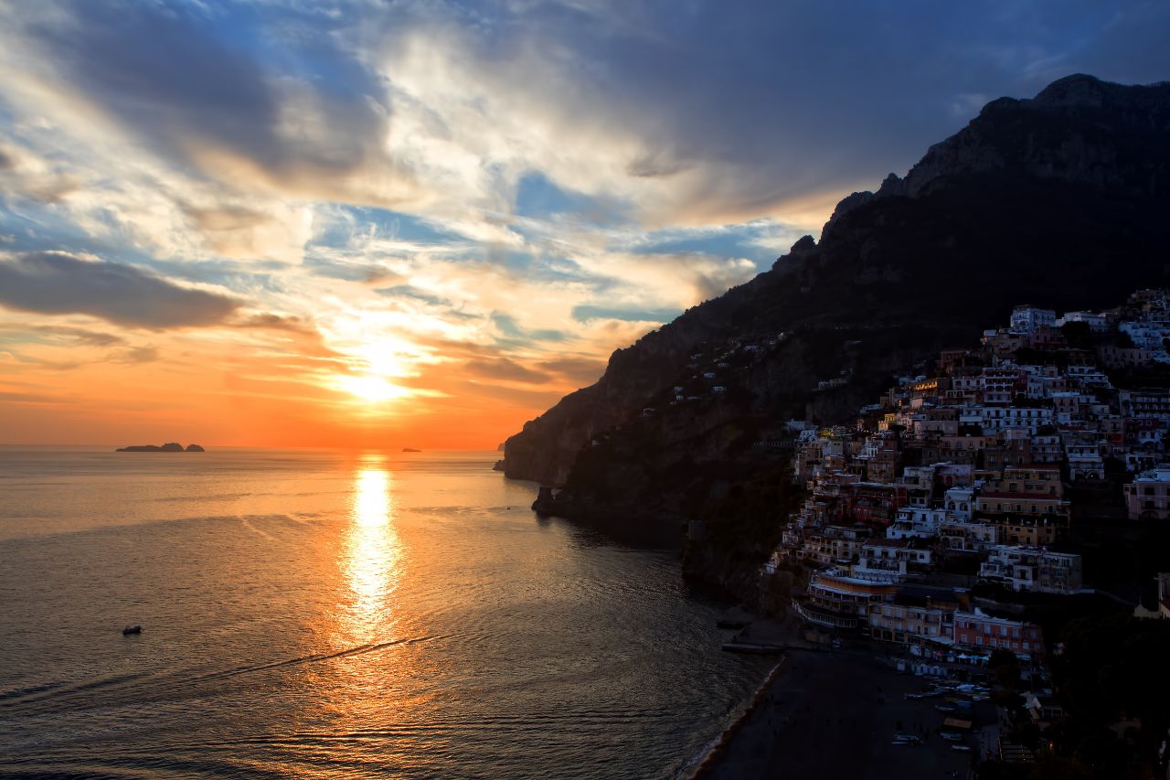 Afternoon view of a town in Positano with a stunning sunset over the sea.