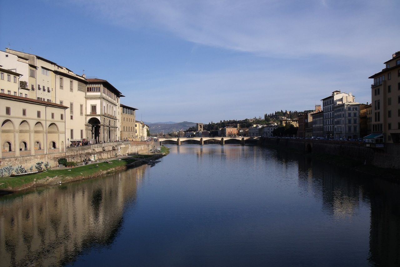 Tourists are walking along the Arno river in Florence, on a sunny day in May