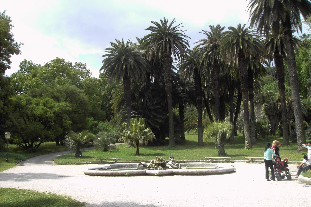 A family is resting on a bench near the fountain in the botanical garden of Rome