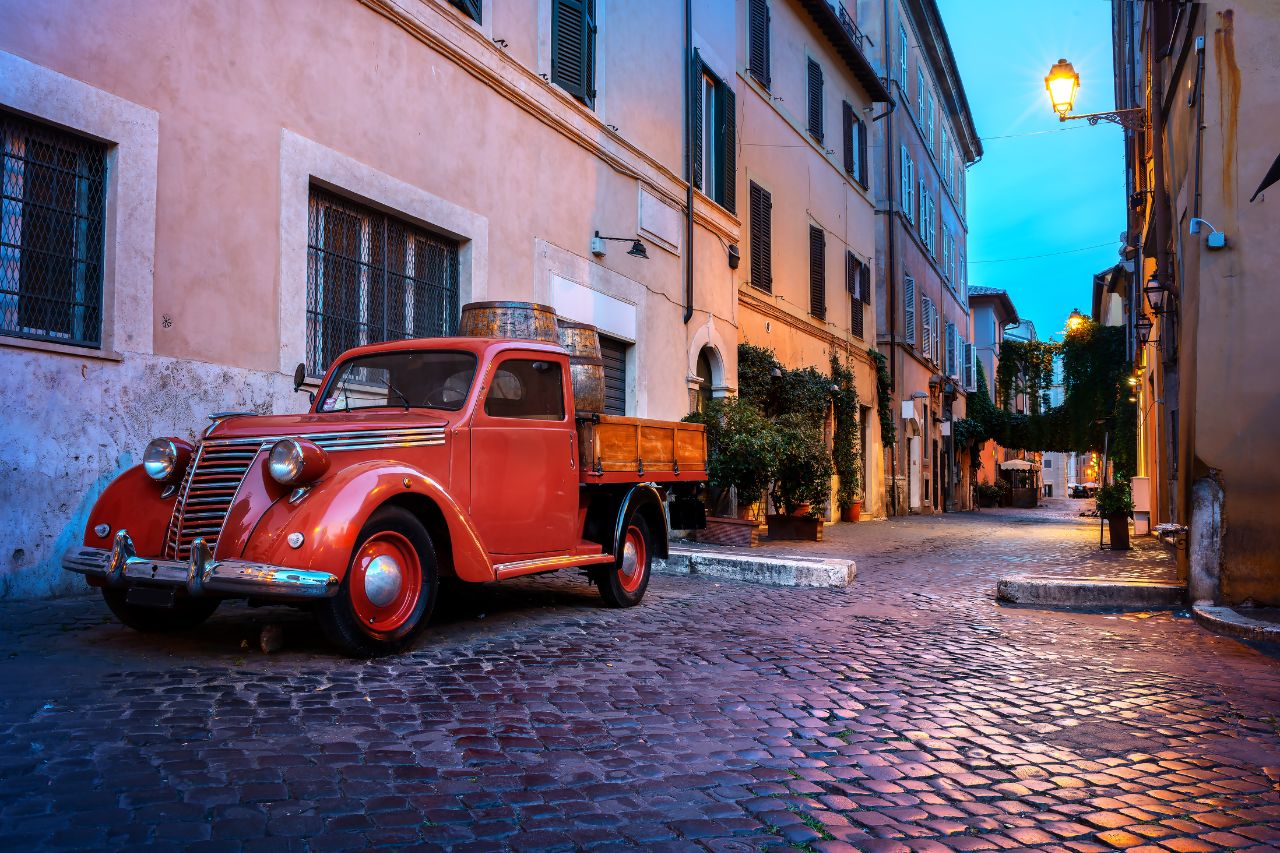 "Image: A charming evening scene in Trastevere, where warm, soft lights illuminate the cobbled streets, creating a magical atmosphere."