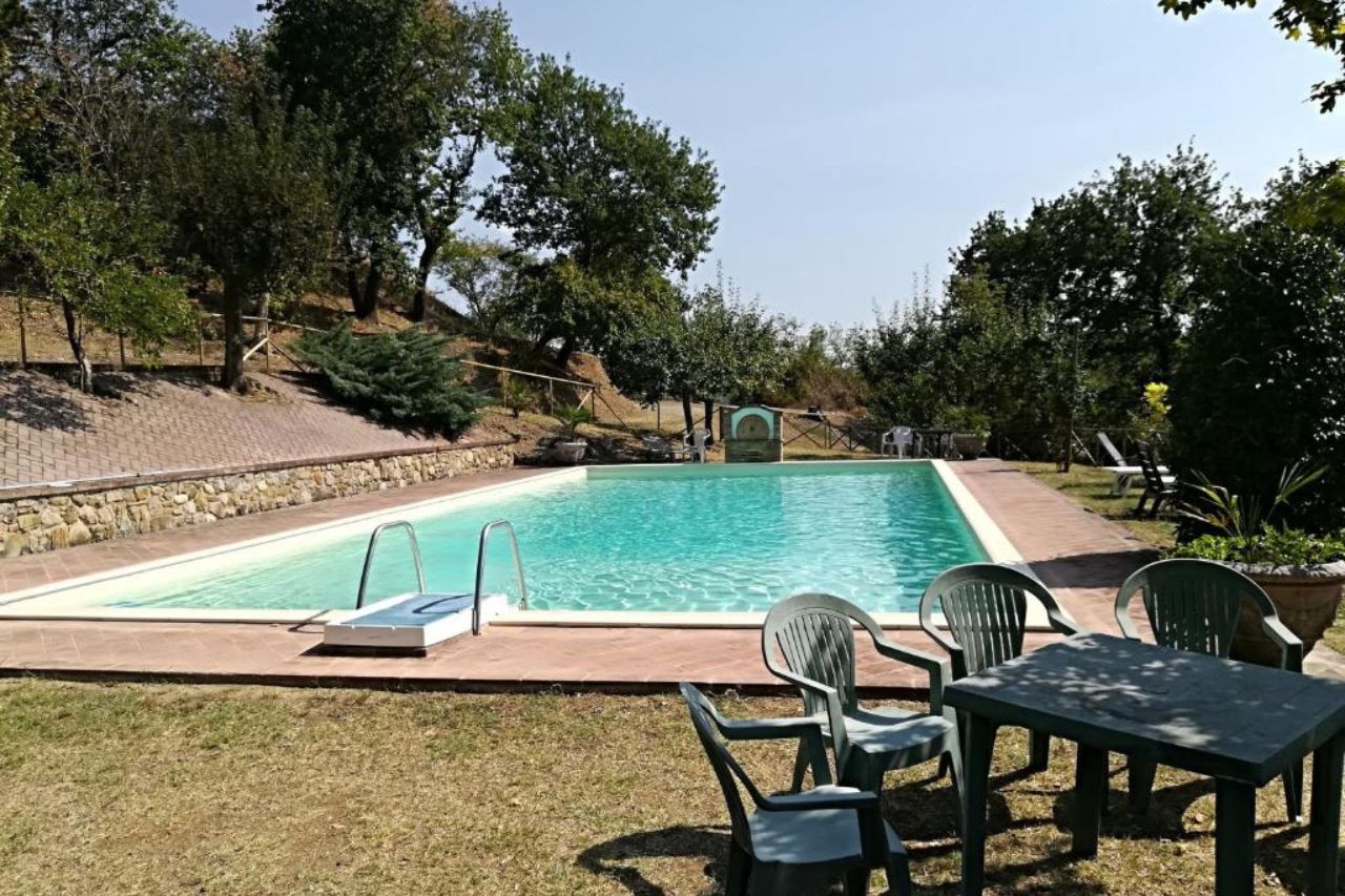 View of the outdoor swimming pool during daytime surrounded by trees and plants located at Agriturismo La Manonera