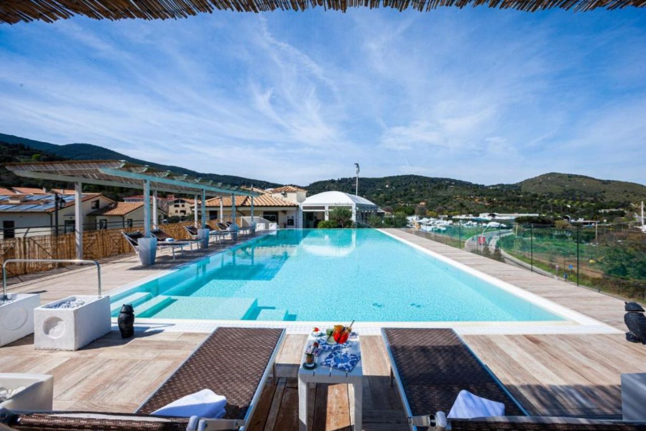 Outdoor swimming pool with beautiful view of mountain and city at A Point Porto Ercole Resort & Spa