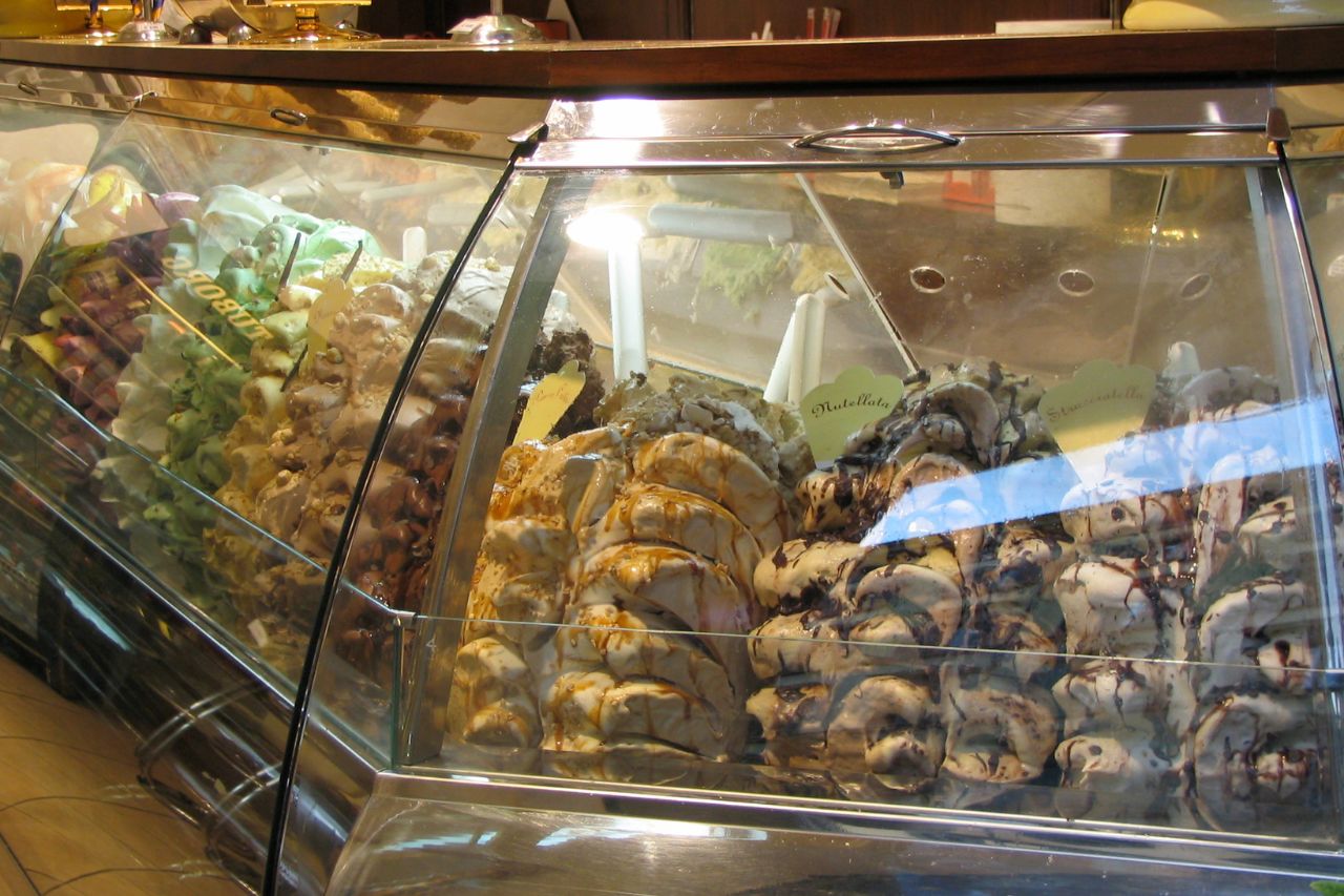 An ice cream shop counter with many flavors of ice cream