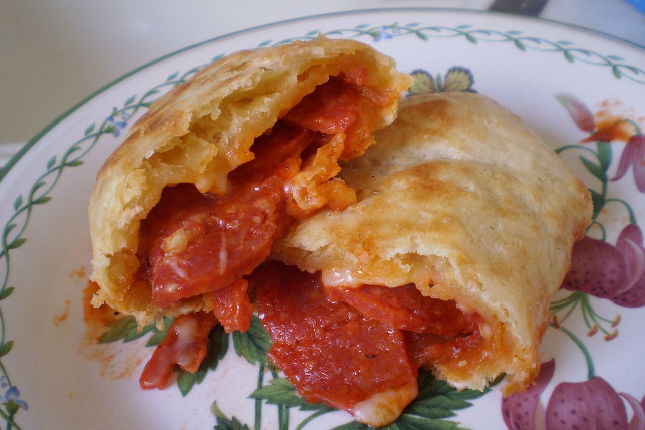 Golden-brown Calzone, a folded Italian pizza filled with tomato sauce, cheese, and toppings.