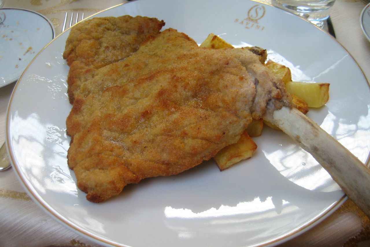 A plate featuring Cotoletta, a traditional Italian dish of breaded and fried cutlet.