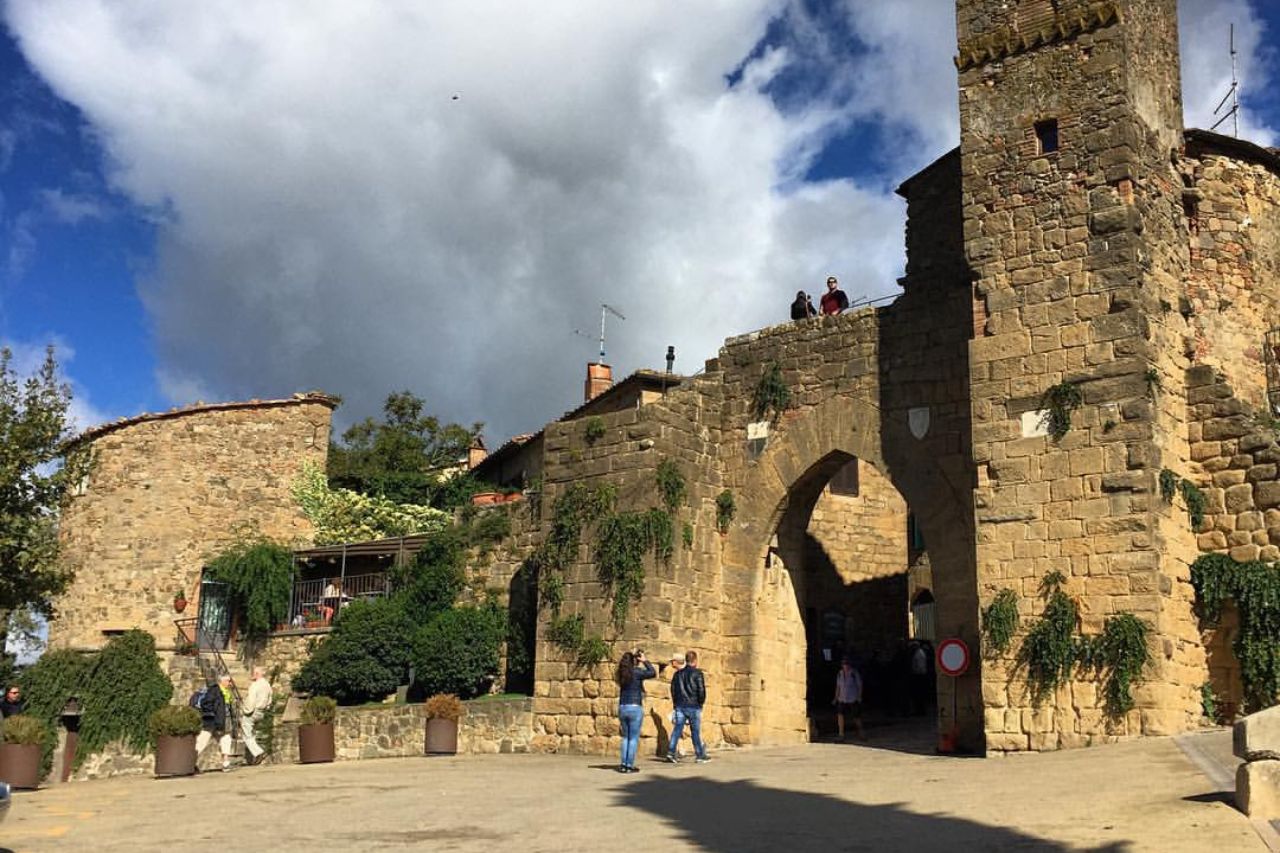Tourists are photographing the entrance to the historic town of Monticchiello, in Tuscany