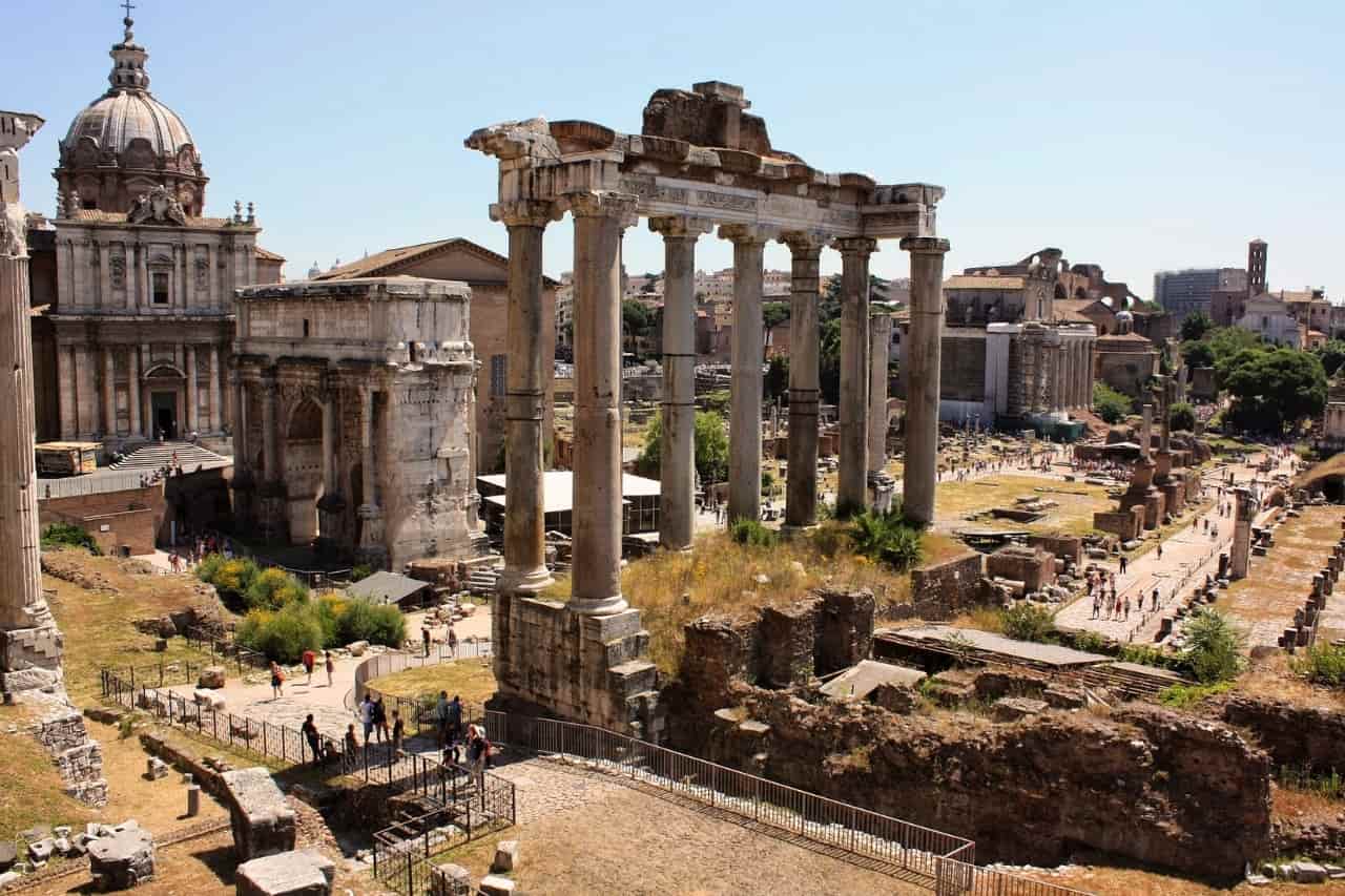 The Roman Forum in Rome, Italy, featuring ancient ruins, columns, and remnants of historical structures amidst a scenic landscape