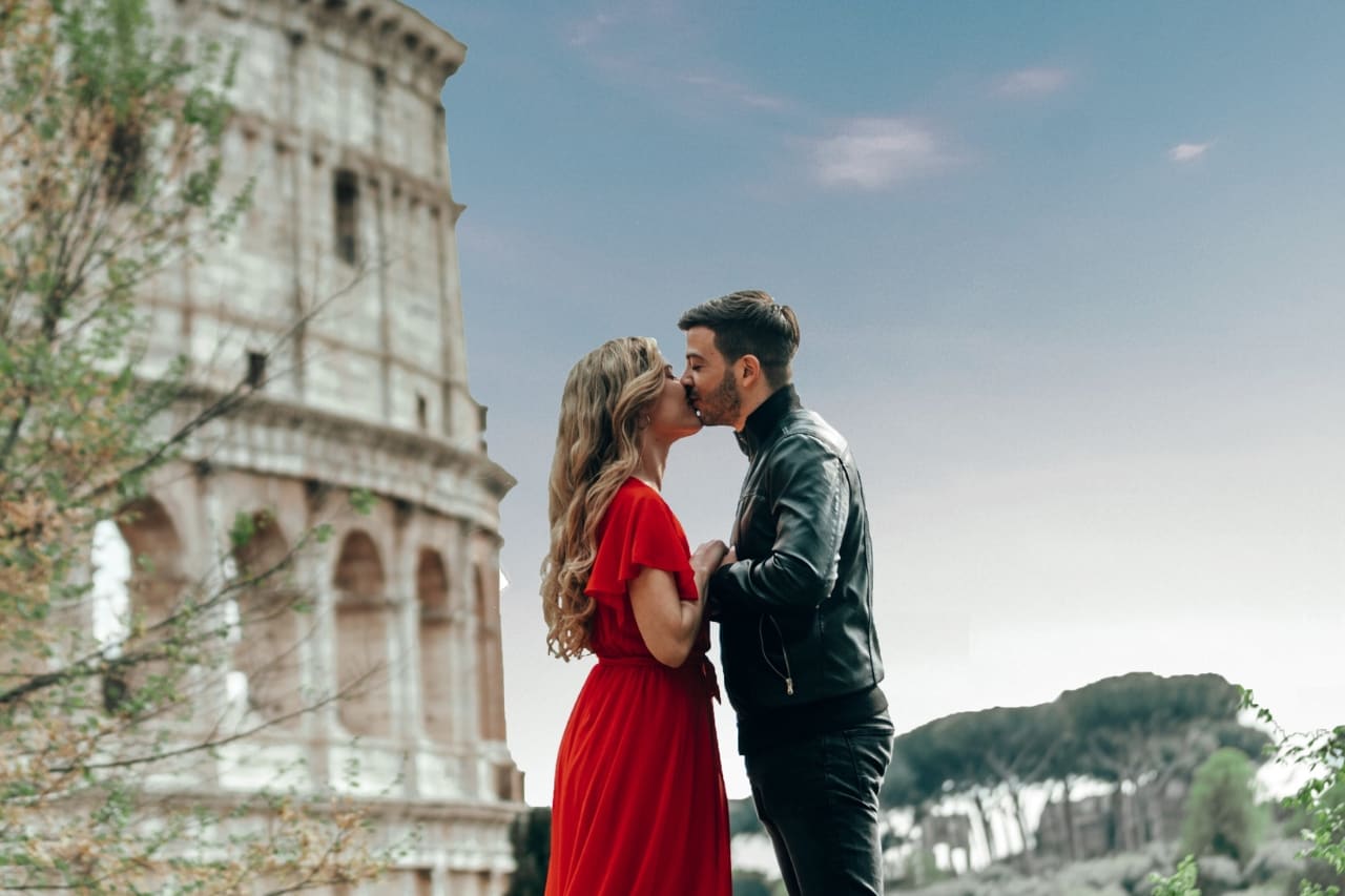Romantic young couple kissing next to the Colosseum, in Rome