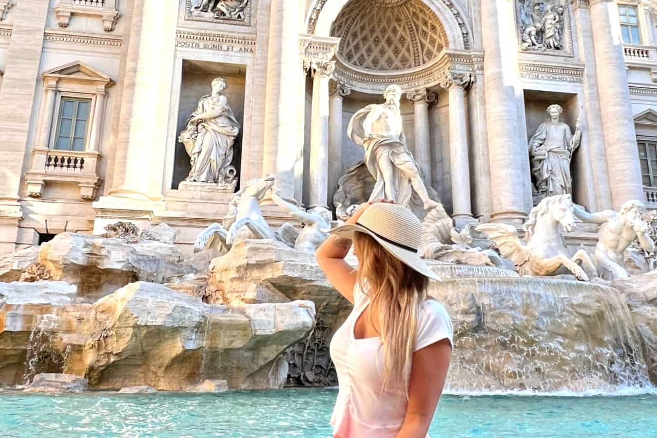 Young woman tossing a coin at the Trevi Fountain in Rome.