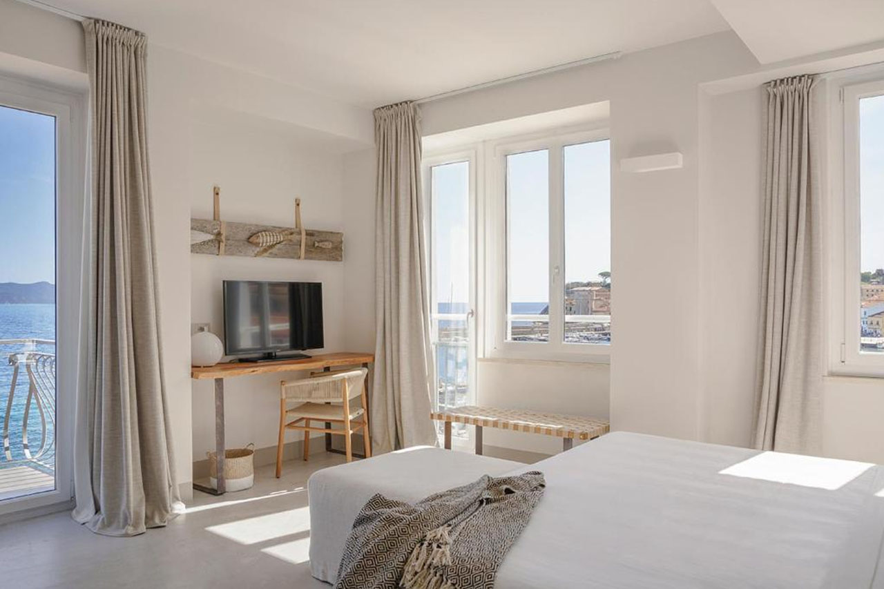 Elegant bedroom with an overlooking view of the sea from the window in La Guardia Hotel