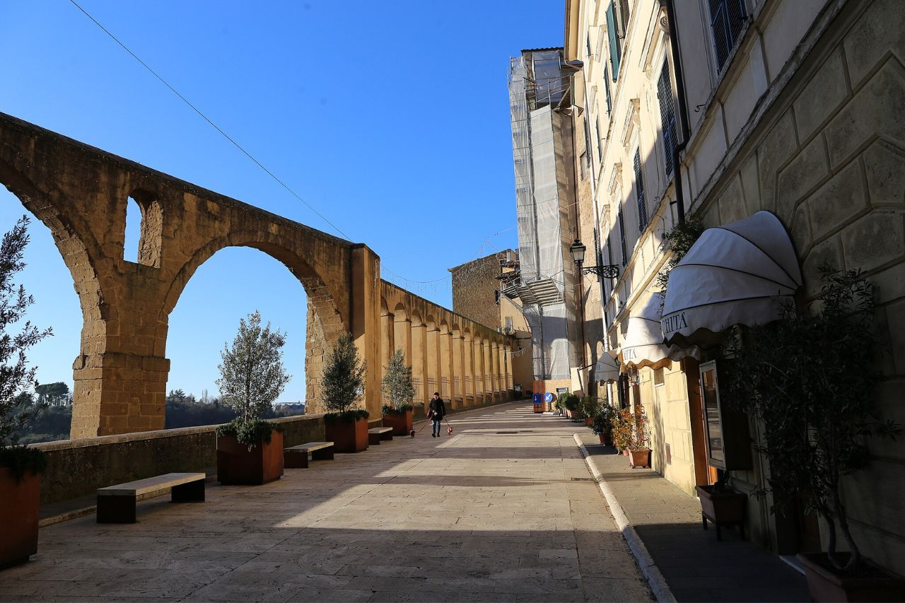 Tourists stroll near the Medici Aqueduct in Pitigliano, Tuscany